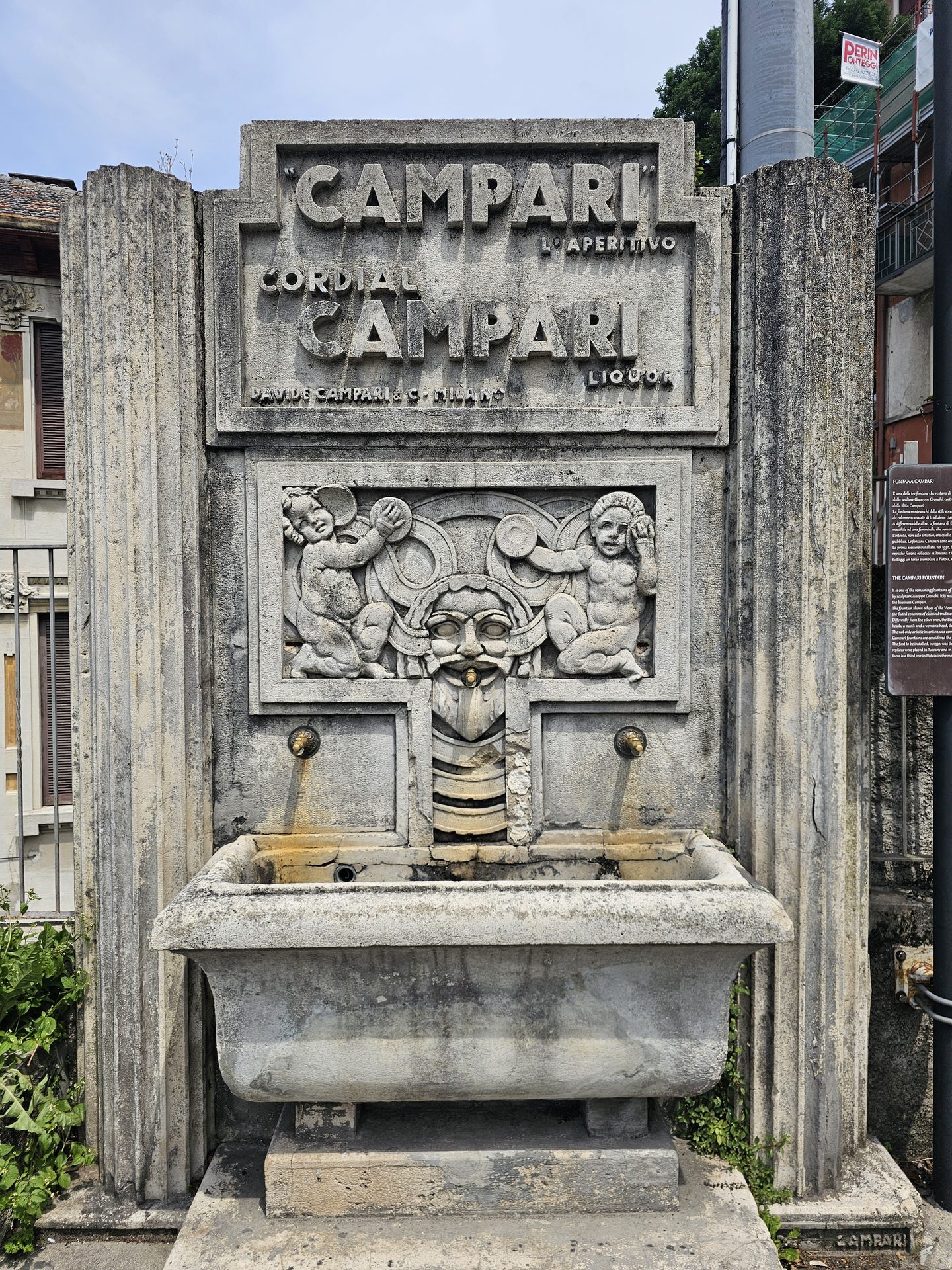 An old carved stone Campari fountain set into a wall on the path up to Brunate