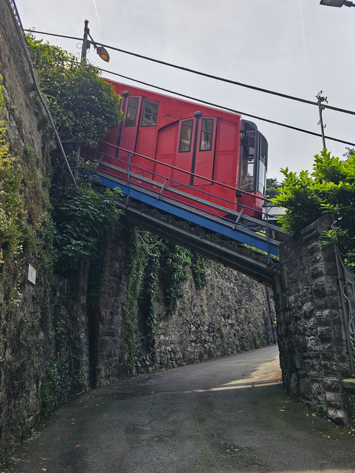 The red Como–Brunate funicular crossing over a walled lane on its way up the hill